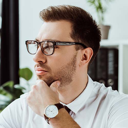 handsome pensive businessman with paperwork and laptop at workspace